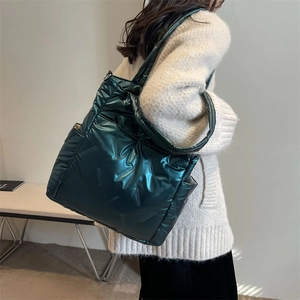 Quilted dark green crossbody bag with metallic finish shown on model in neutral light