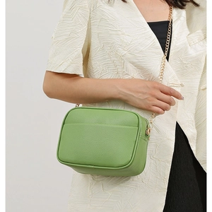 Litchi texture grass green shoulder bag with gold chain strap worn on cream blazer