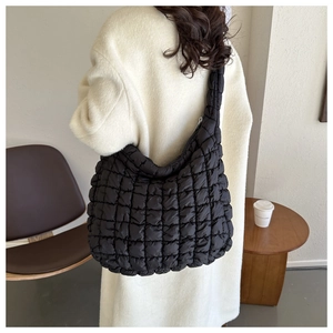Détail d'un sac cabas matelassé noir avec bandoulière rembourrée dans un café confortable