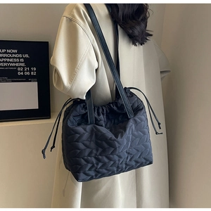 Detail view of large black quilted shoulder bag with drawstring and leather straps
