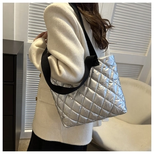 Close-up of silver quilted tote bag with metallic gloss and wide black shoulder strap