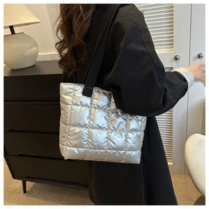 Silver quilted tote bag with metallic nylon texture and black shoulder strap on model