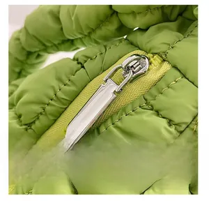 Close-up of the smooth silver metal zipper on a grass green quilted cloud tote bag