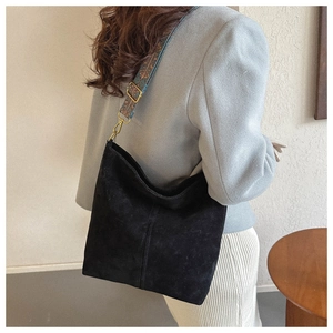 Detail of black matte suede shoulder bag with colorful ethnic embroidered wide strap