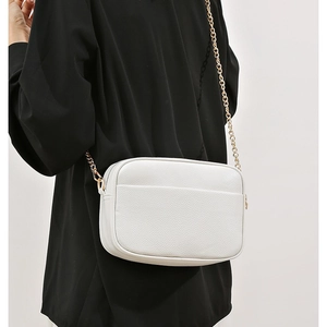 White pebbled leather crossbody camera bag with gold chain strap and stylish shoulder strap