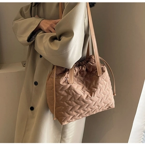 Detailed side view of a brown quilted tote bag with leaf pattern and drawstring closure