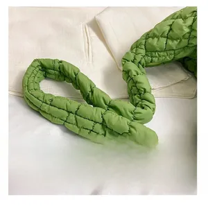 Close-up of green quilted puffy shoulder strap on soft padded cloud bag with nylon texture