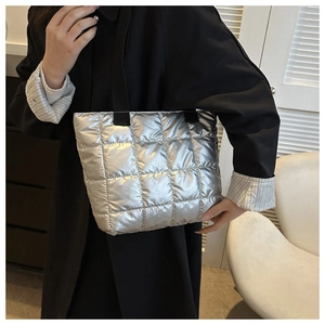 Silver quilted down tote bag with metallic finish shown on model in black trench coat