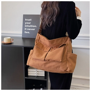 Brown canvas crossbody bag with multiple utility pockets and wide strap back view