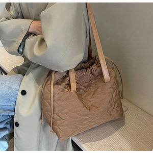 Detail of a brown quilted nylon shoulder bag with wavy stitching and drawstring closure