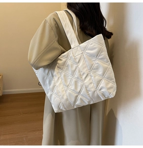 Detail of white quilted tote bag with puffer nylon texture and diamond stitching design
