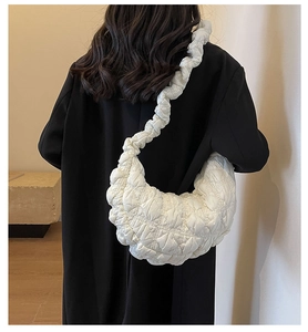 Detailed close-up of white croissant bag with pleated texture on black coat