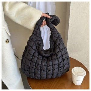 Détail d'un sac matelassé noir avec une poignée nouée unique pour un style minimaliste