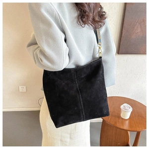 Detailed view of black suede tote bag with ethnic pattern strap and gold hardware