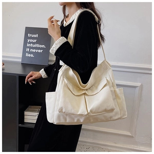 Detail view of large cream canvas tote bag with functional pockets and shoulder strap