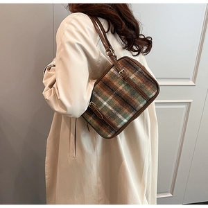 Detail of tweed and leather crossbody bag worn with a stylish beige autumn trench coat