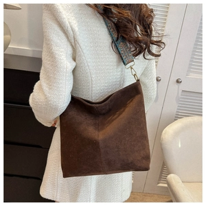 Brown suede crossbody bag with ethnic style embroidered strap shown in a lifestyle setting