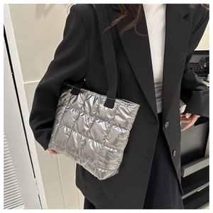 Detailed close-up of a silver quilted tote bag featuring metallic glossy finish and fabric strap