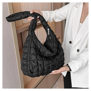 Fashionable black quilted cloud bag shown on model with wide strap and zip closure