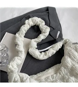 Detail of white quilted puffy cloud bag on a dark blazer with minimalist city vibes