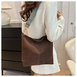 Brown frosted leather Hobo bag with ethnic embroidery strap on white tweed jacket background