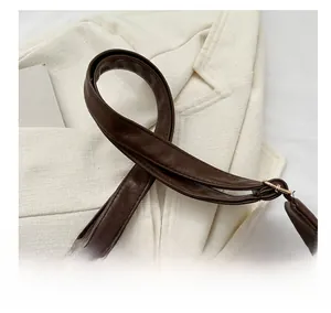 Detailed close-up of dark brown PU leather strap with stitching and gold buckle
