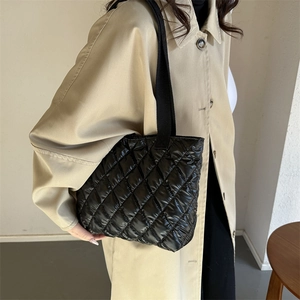 Minimalist black quilted nylon tote bag with rhombus stitching shown on a model