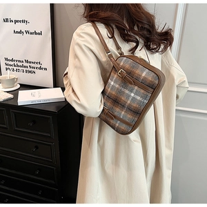 Detail of vintage plaid woolen backpack with brown leather straps and gold metal buckle