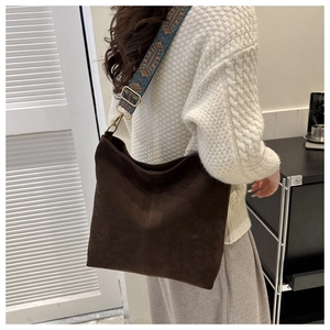 Detail of dark brown suede hobo bag featuring embroidered ethnic style wide shoulder strap