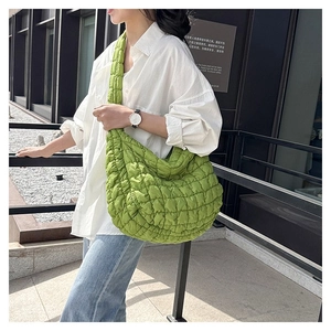 Detail of green quilted bubble shoulder bag with soft textured puffer fabric pattern