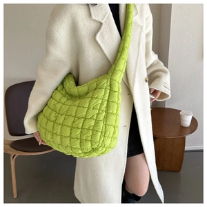 Sac hobo matelassé vert fluo porté avec un manteau en laine blanc dans un décor moderne