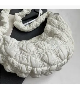 Detail of white quilted puffy handbag showing bubbly nylon texture and ruched shoulder strap
