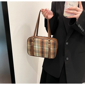 Detail view of the brown green plaid shoulder bag with vintage leather buckle straps