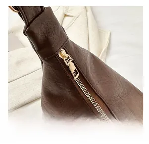 Detail of smooth gold zipper and knotted strap on dark brown leather tote bag