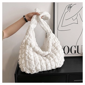 Detail of white quilted cloud bag featuring a knotted handle and silver metal zipper