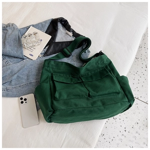 Detail of dark green canvas messenger bag with double front pockets and adjustable strap