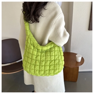 Sac bandoulière matelassé vert vif porté par un mannequin en manteau d'hiver beige