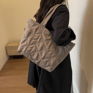 Chic quilted taupe tote bag in puffy nylon fabric, worn over shoulder in a modern setting