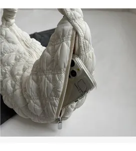 Detail view of white quilted bag side zipper pocket with smartphone showing storage capacity