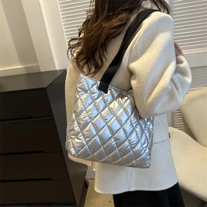 Silver quilted tote bag with metallic texture and black shoulder strap for trendy women