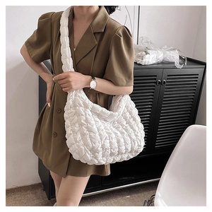 Macro shot of a white quilted puff tote bag with soft pleated texture and wide shoulder strap
