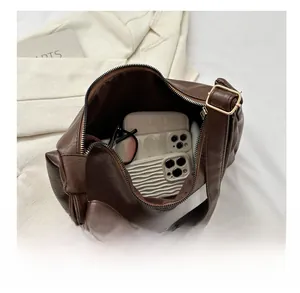 Top view of spacious dark brown PU leather tote bag interior holding phones and glasses