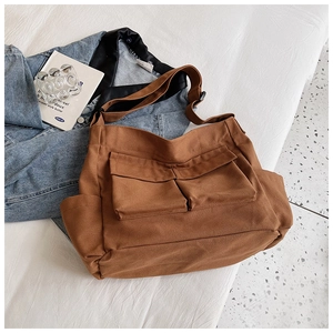 Detail of caramel brown canvas bag with two large front pockets and adjustable strap