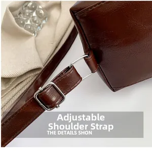 Détail de la bandoulière en cuir PU marron foncé avec boucle de réglage argentée sur le sac