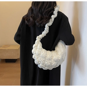 White puffy cloud bag with quilted bubble texture worn over a stylish black coat