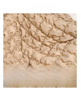 Detail of beige quilted cloud bag showing smooth satin fabric and textured stitching