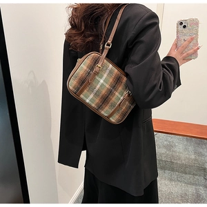 Detail of vintage plaid tweed shoulder bag with brown leather trim on black blazer