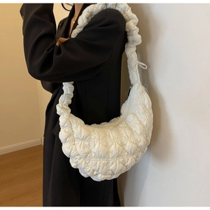 Detail of white quilted nylon cloud bag with wide pleated strap and silver zipper closure