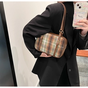 Detail of wool blend plaid pattern with brown leather trim and vintage gold buckle on handbag
