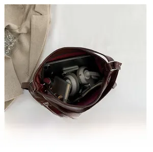 Vue macro de la grande capacité intérieure du sac à bandoulière en PU marron avec objets